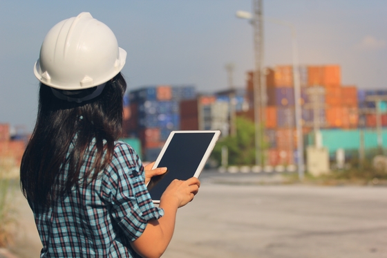 Woman in hard hat holding ipad checking cargo
