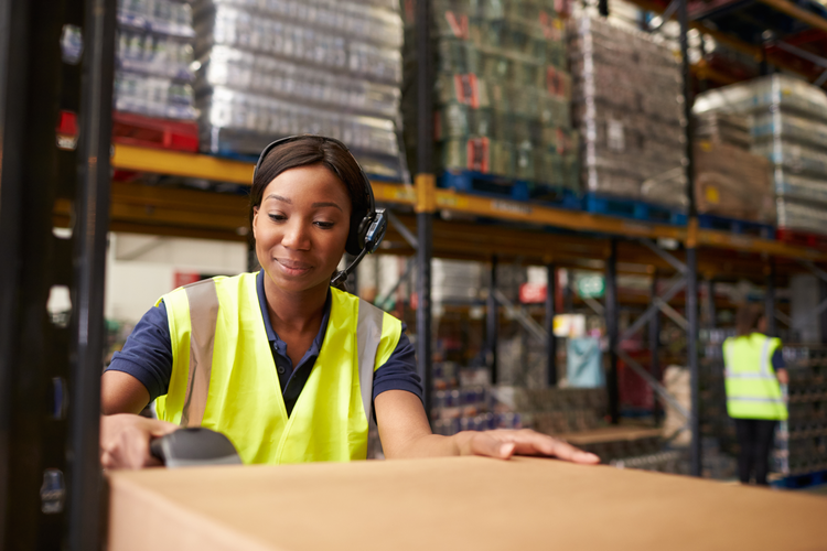 Woman in warehouse scanning barcode on a package