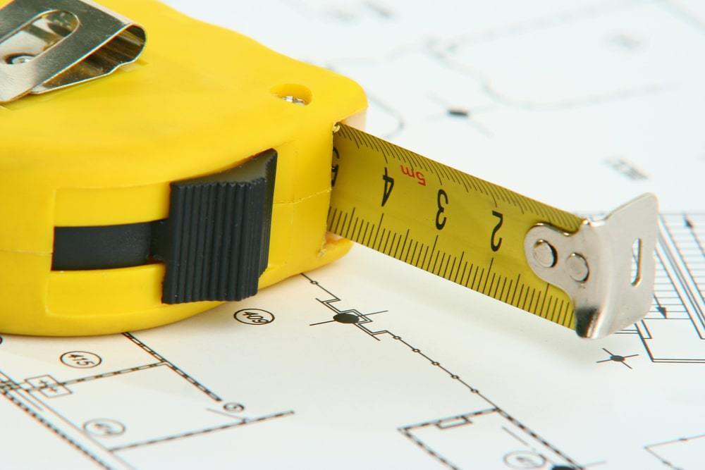 Close up of person cutting white foam board paper with an exacto knife and  measuring with metal ruler Stock Photo