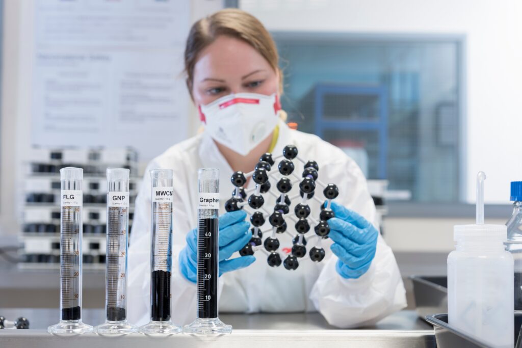 Female scientist with graphene nano material molecular model in graphene processing factory