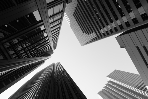 Looking up at skyscrapers from ground level in black and white