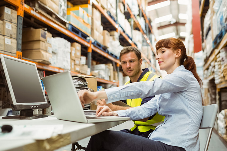 Two people in a warehouse looking at a laptop