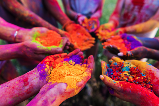 People holding colorful powder at a Holi celebration.