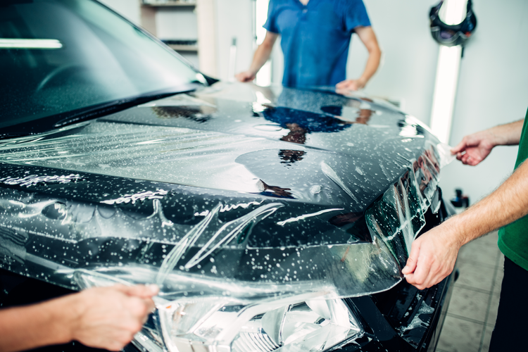 three people putting on a car film 