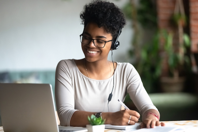 Woman writing and looking at her laptop
