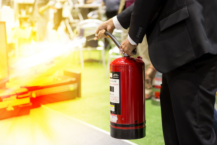 Someone in a suit using a fire extinguisher