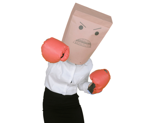 Woman wearing boxing gloves and a paper bag with an angry expression drawn on it