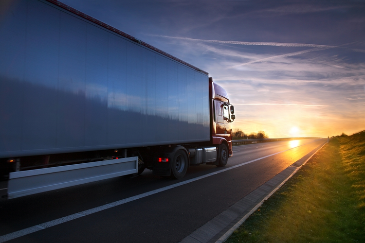 Tractor trailer on the road at sunset.