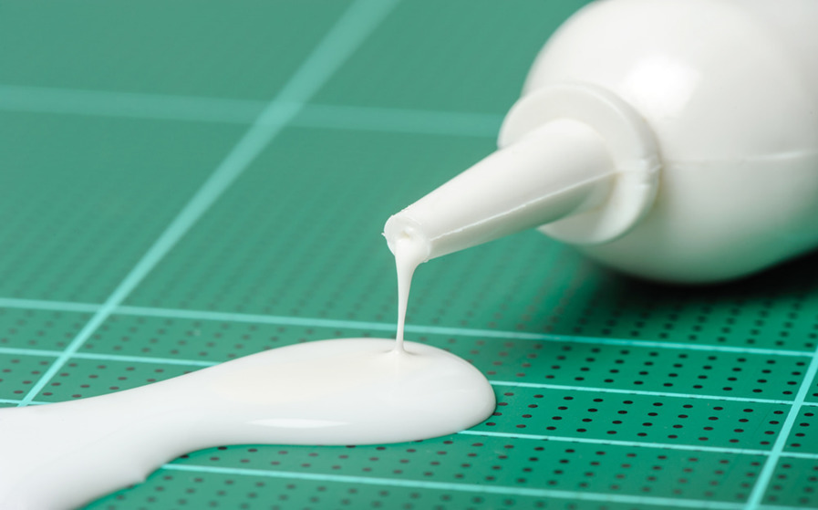 Close-up of white glue dripping on green mat.