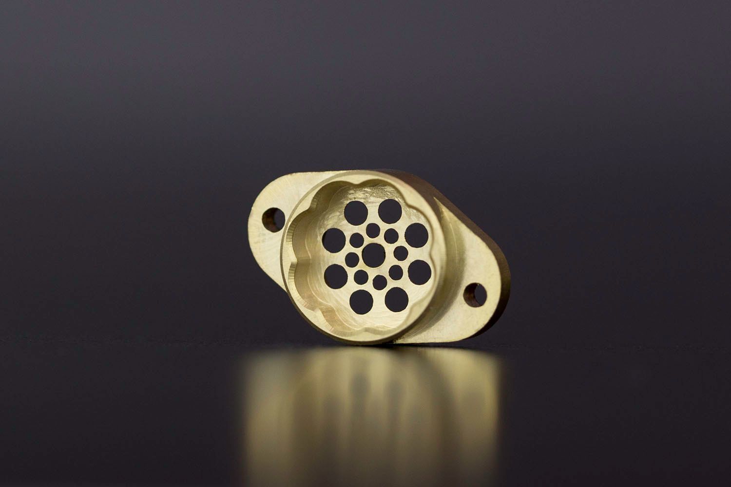 A brass part featuring drilled holes of various sizes.