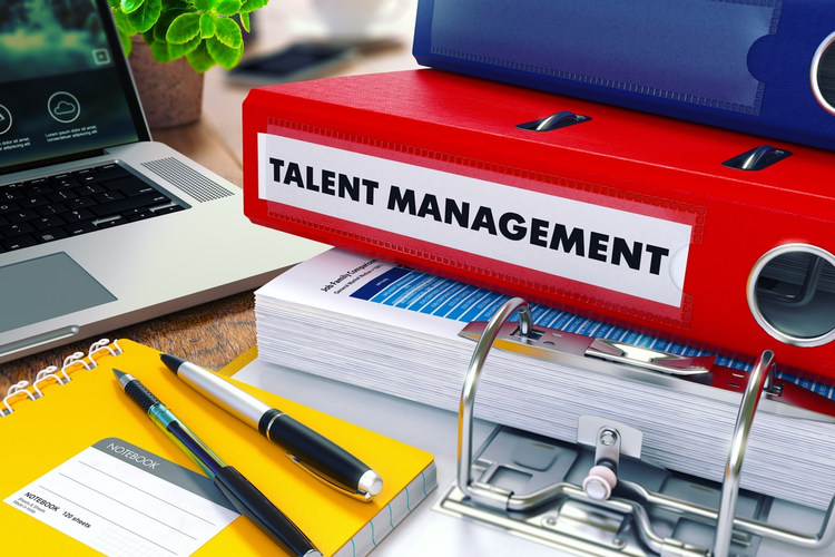 Red binder labeled 'Talent Management' on office desk with other office supplies.