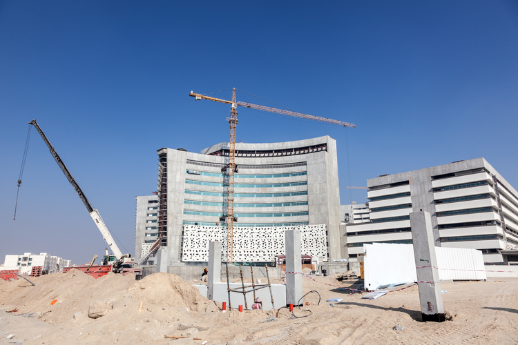 Construction zone with a partially-completed hospital in the background