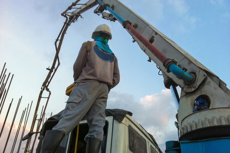 Construction worker controlling boom truck with concrete pump
