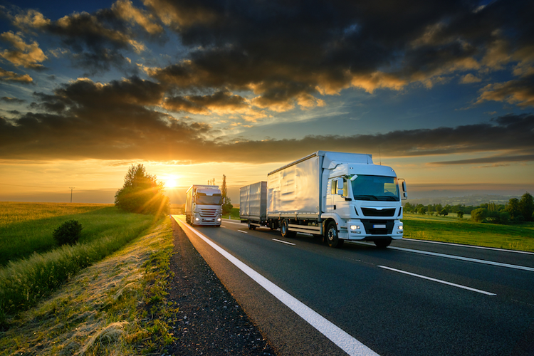 Trucks on highway at sunset