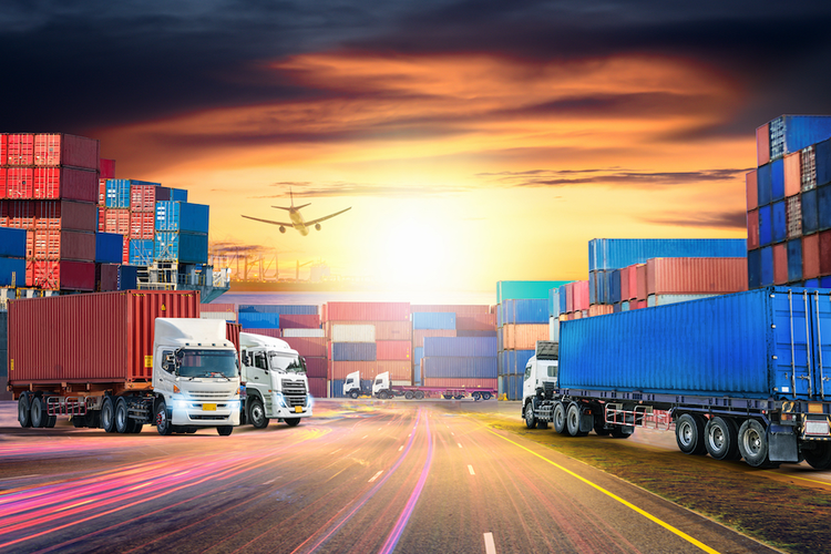 Trucks in loading truck at sunset with airplane in background