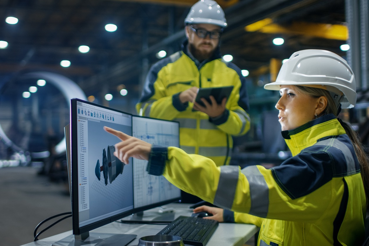 Woman in manufacturing role gesturing to 3D image on computer screen