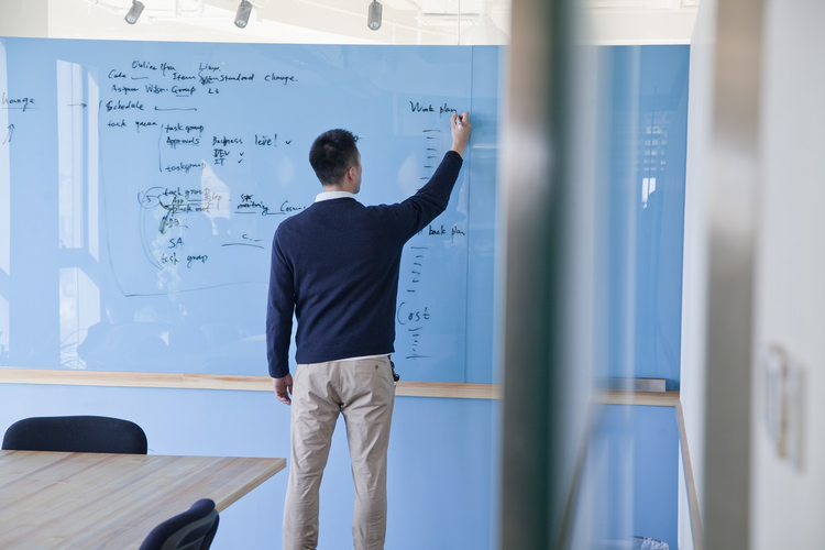 Businessman writing on glass marker board in office setting