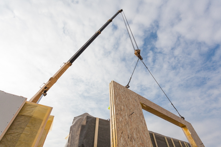 Crane installing structural panel in modular construction job