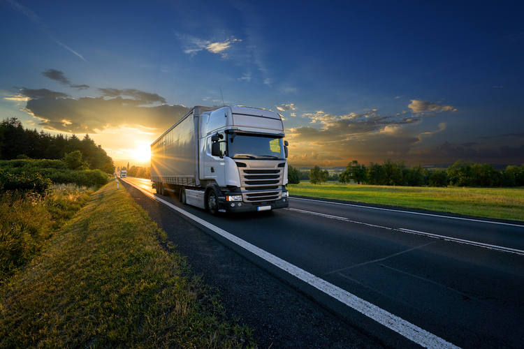 Truck driving on highway with sunset in background