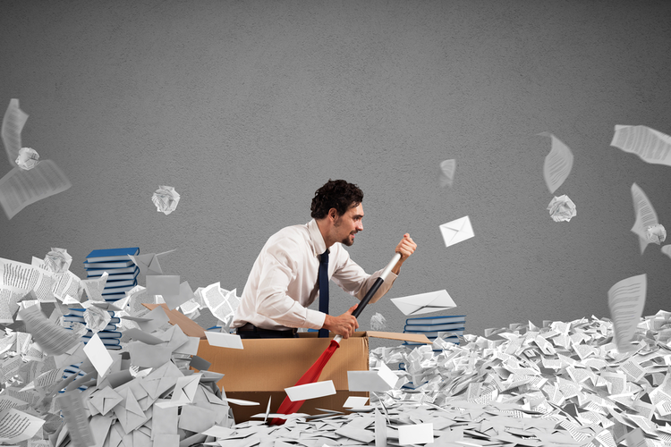 Man in cardboard box boat rowing through bureaucratic paperwork