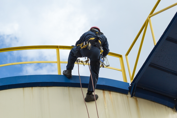 Worker inspecting tank.