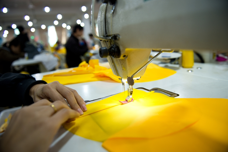 Hand sewing a material on a machine.