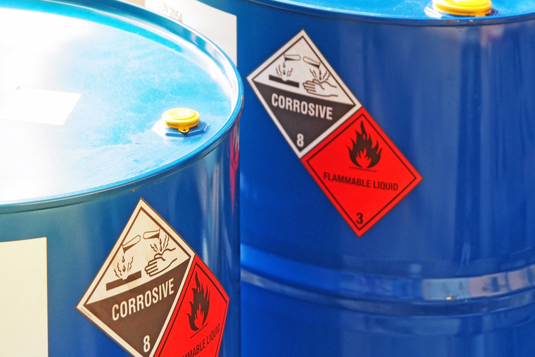 Close-up image of two blue chemical barrels with warning labels.